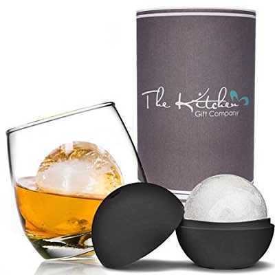 Wackelglas mit Whisky und großer Eiskugel neben grauer Geschenkverpackung und Eiskugelform
