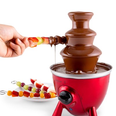 Roter dreistöckiger Schokobrunnen mit Obstspießen und Früchteteller
